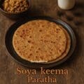 Soya keema paratha served hot with onion raita and pickle on a rustic ceramic plate