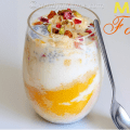Layered mango falooda served in a tall glass with ice cream and chopped nuts