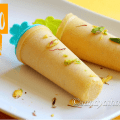 Creamy mango kulfi popsicles garnished with chopped nuts and saffron strands on a rustic plate