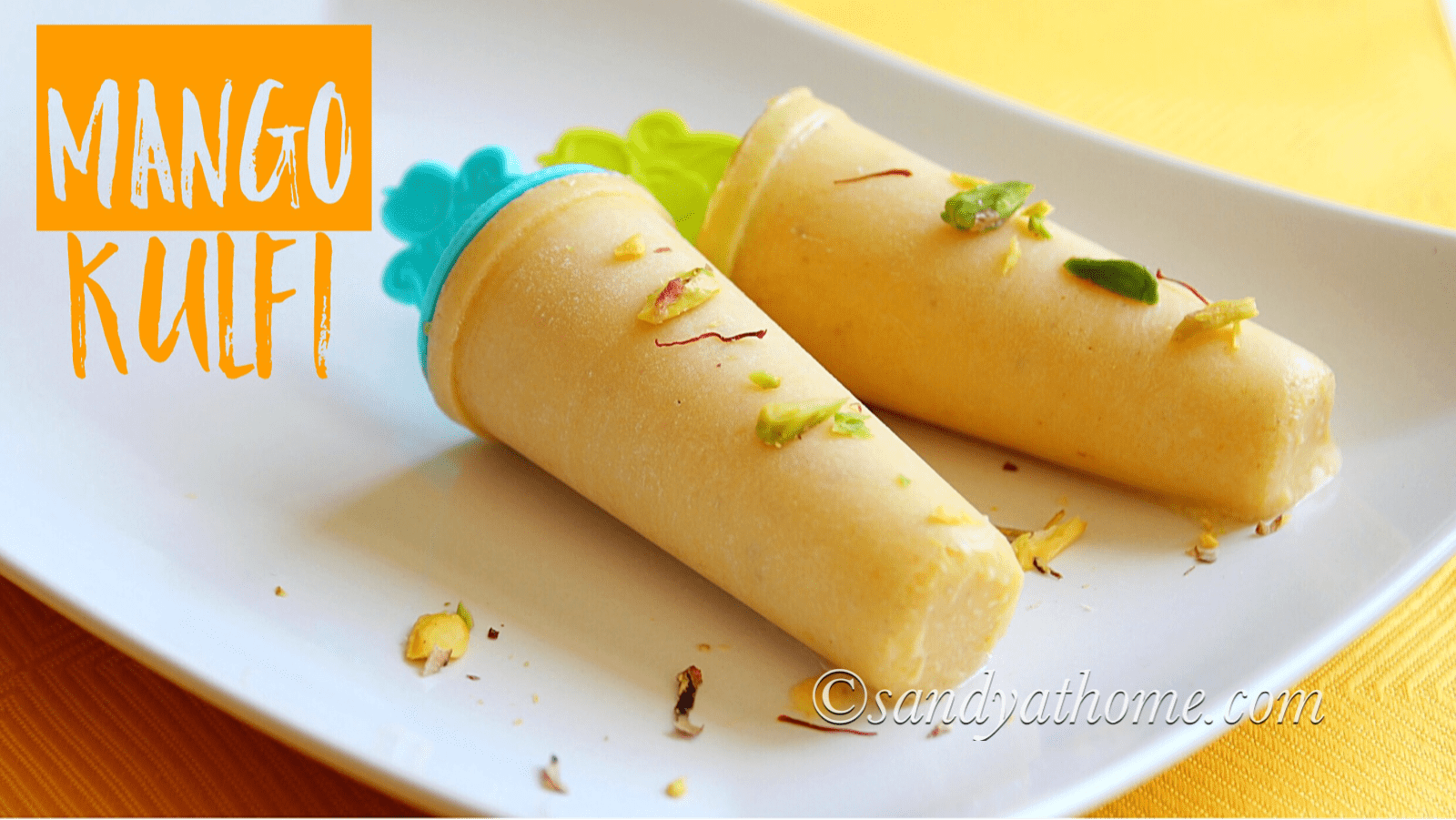 Creamy mango kulfi popsicles garnished with chopped nuts and saffron strands on a rustic plate