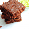 A soft, chocolatey eggless brownie made with zucchini, served on a white plate with crumbs around