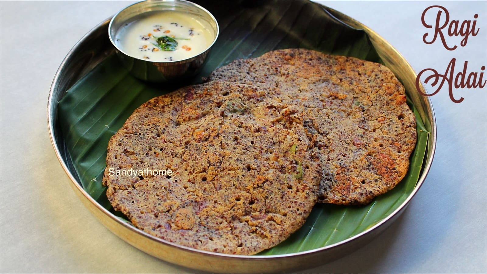 Traditional ragi adai batter dosa made with whole millets and dals being spread on a hot iron pan.