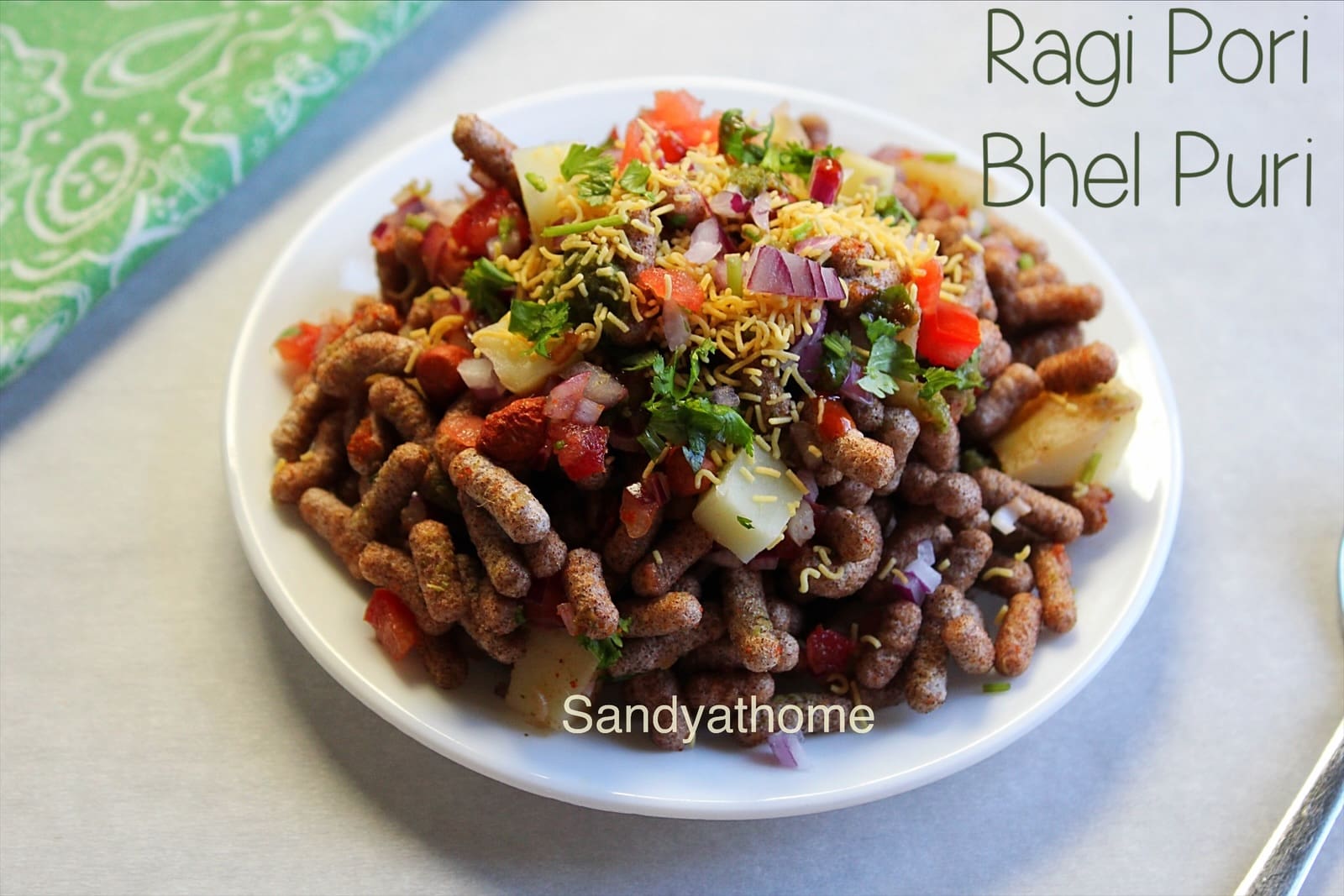 Puffed ragi chaat using ragi pori in place of murmura, presented as bhel puri with onion, tomato, and coriander.