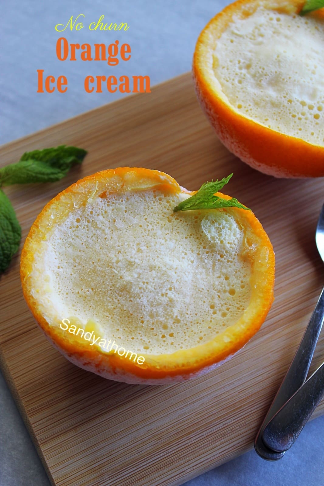 Real orange ice cream served in halved orange shells, flat set without scoop, summer dessert with fresh mint garnish