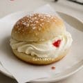 Soft and fluffy eggless Indian bakery-style cream bun filled with buttercream and topped with powdered sugar.