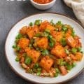 Golden crispy idli pieces stir-fried with harissa sauce, onions, and green capsicum in Indo-Chinese style