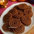 Close-up of crispy homemade ragi chakli (finger millet murukku) stacked on a white plate — traditional South Indian Diwali snack made without rice flour.