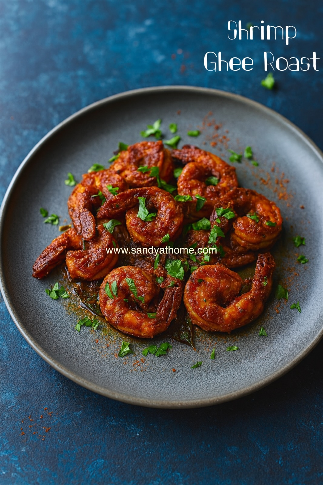 Close-up of prawns roasting in ghee with curry leaves and spice marinade.